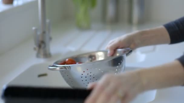 Женщина моет помидоры в стальном дуршлаге — стоковое видео