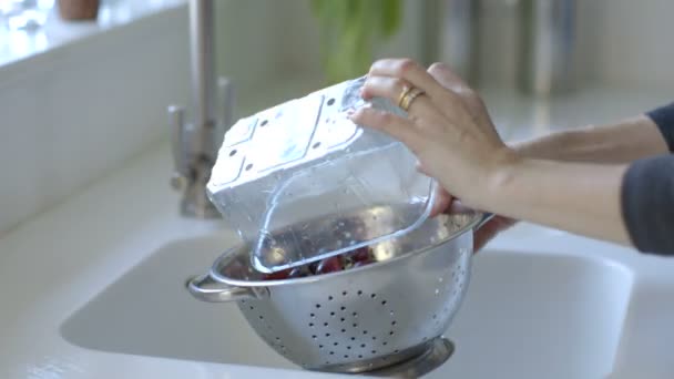 Женщина моет красный виноград в стальной дуршлаг — стоковое видео