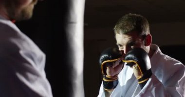 Eğitmen ile bir genç atlet uygulama boks kum torbasına yavaş hareket ile.