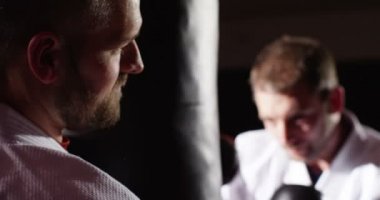 Eğitmen ile bir genç atlet uygulama boks kum torbasına yavaş hareket ile.