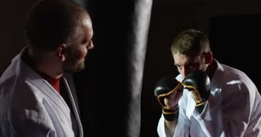 Eğitmen bir kum torbası ile pratik bir genç sporcu ile.