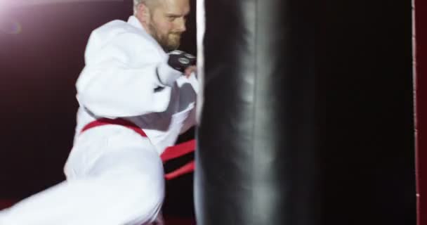 A young athlete in kimono kicks a bag. — Stock Video