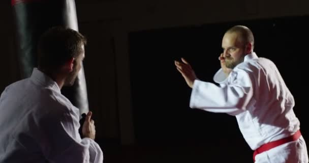 Entraîneur avec un jeune athlète pratiquant avec un sac de boxe au ralenti . — Video