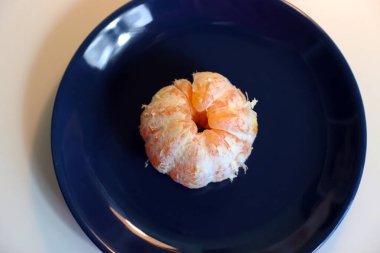 Mavi bir tabakta kabuksuz mandalina.