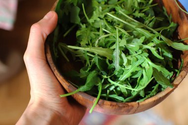 Elin ahşap bir kase roka tutuyor..