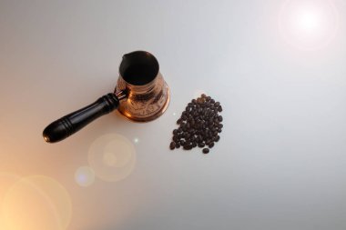 Türk ve kahve taneleri beyaz bir masada parlıyor.