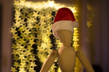 Parlak yıldızlarla dolu bulanık bir arkaplan önünde Noel Baba şapkası olan tahta manken.