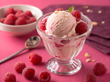 Taze ahududu ve nane yaprağıyla süslenmiş cam bir tabakta ahududu dondurmasının yakından görüntüsü.