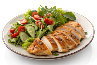 Dilimlenmiş ızgara tavuk göğsünün yanında taze yeşil salata, salatalık dilimlenmiş salatalık ve sulu vişne domatesli lezzetli ve sağlıklı bir yemek.