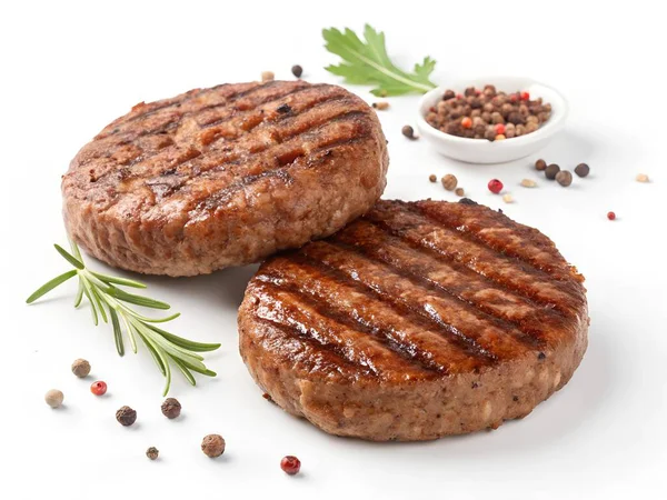 İki taze ızgara sığır eti, temiz beyaz bir yüzey üzerinde biberiye ve biberiye ile sunulur. Bu da aşçılık hazırlığı duygusunu ve lezzetli malzemeleri çağrıştırır.