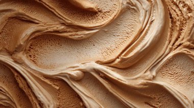 Kahve aromalı dondurmanın detaylı bir yakın çekimi zengin dokusunu kremalı girdaplar ve hava kabarcıklarıyla sergiliyor. Lezzetli bir hoşgörünün görsel bir temsilini sunuyor.