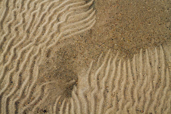 Golvende zandstrand textuur achtergrond closeup — Stockfoto