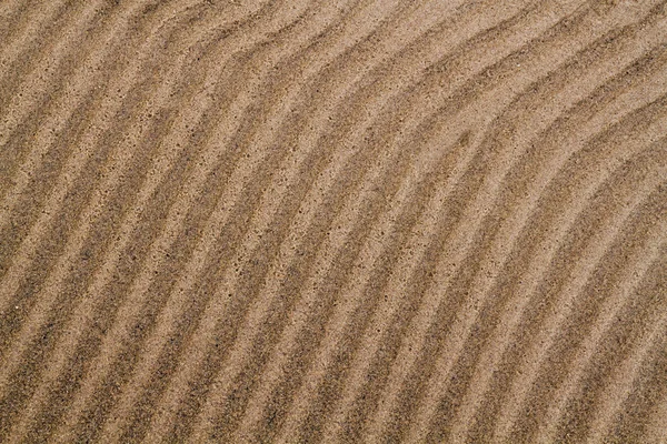 Golvende zandstrand textuur achtergrond closeup — Stockfoto