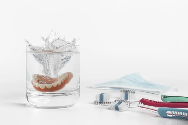 Concept de prothèses dentaires avec verre, masque et brosse à dents — Photo