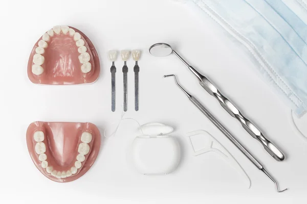 Prótesis dentales al lado de hilo dental y metal pick and mirror — Foto de Stock