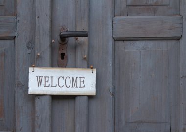 Welcome sign hanging on an old wooden door clipart