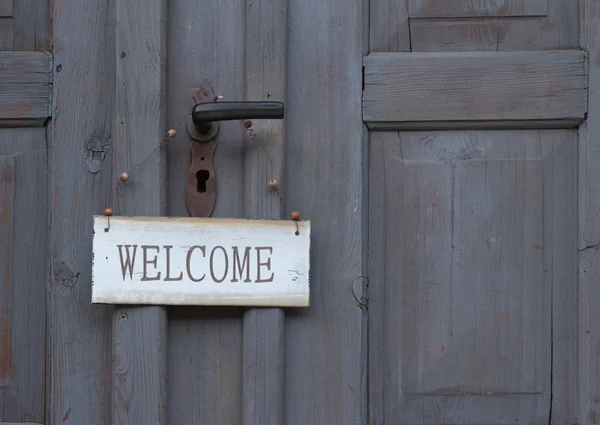 Panneau de bienvenue accroché à une vieille porte en bois — Photo