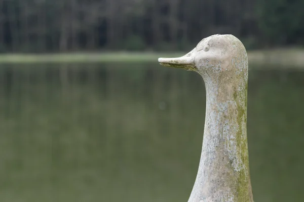Duck or goose statue alongside a lake