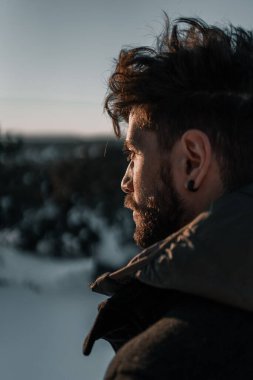 Gün batımında kar altında dağda bir adamın portresi.