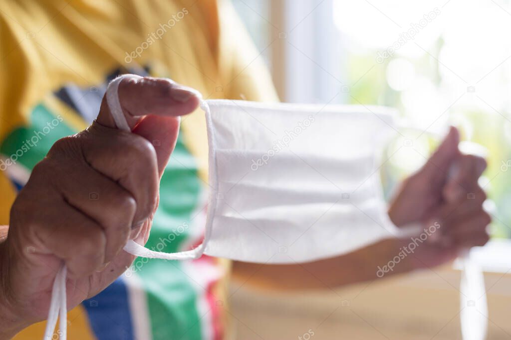 old lady holding protective mask against corona virus wearing t-shirt from south africa