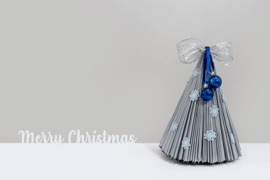 Topları ve kurdelesi olan gri Noel ağacı. Mutlu Noeller yazılı.