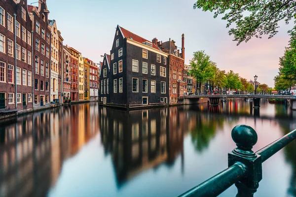 Amsterdam 'da gün batımı, açık bir günde, önünde ağaçla birlikte kanala yansıyor.