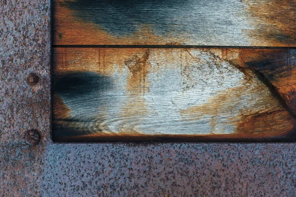 Eski paslı ahşap panel, mavi ve turuncu renkli, metal çerçeveli.