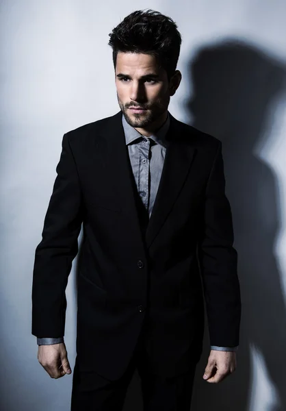 Joven guapo en traje sobre fondo gris. Hombre de negocios — Foto de Stock