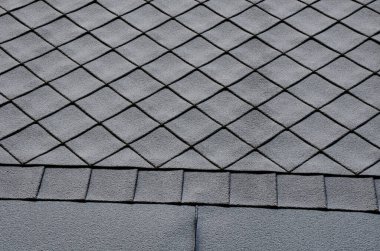 Pencereli gri çatı kiremitleri kare şablon. Eğik bir şekilde yerleştirildi. Kare şablon. Çerçevelemek ve daha iyi bir kar tabakasını yırtmak için çatının alt kısmı metal şeritten oluşur..