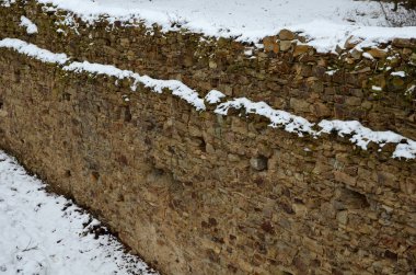 Galeri boyunca ve kirişlerin zemininde açıkları olan eski kalenin yüksek koruma duvarı. Karla kaplı.