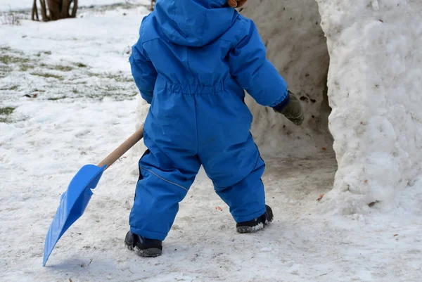 Egy Téli Kezeslábasban Járó Kisgyerek Kék Műanyag Lapáttal Hóban Sétál — Stock Fotó