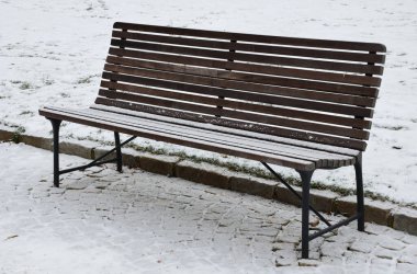 Parktaki beton duvarın yanındaki karlı banklar. Paving ve metal çitler süs çiçeklerini köpek idrarından korur.