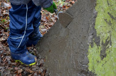 Çamur çimento alçısıyla duvarları fırlatan küçük çocuklar. Babamdan aletler ödünç aldılar. Spatulalar çamur lekesini fayans yapıştırıcısı gibi sürerler. Ormanda askeri barikat beton piramit