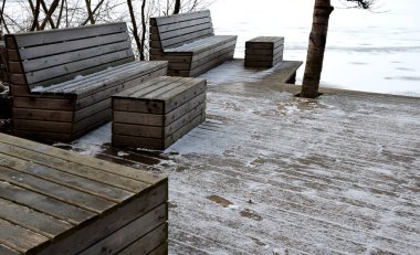 Ormanda su kenarında doğal odunlarla sıralanmış ahşap koltuklar. Güverte terası göletin yanında. Her şey kışın eklemleri olan, sahnedeki deliğinde bir kar ağacı olan tek parça.