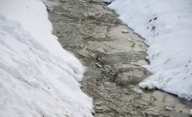 Donmuş akarsu, su açıkça görülebilir, ama buz yavaş yavaş onu kapatıyor. Derin bir vadideki soğuk, dondurucu su manzarası ve çağlayan küçük bir dere.