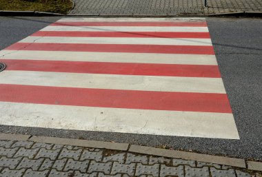 Karşıdan karşıya geçerken, beyaz kırmızı zebra daha iyi görüş ve güvenlik için okula yakın bir yerde, anaokulunda. Kaldırımlar, karşı kıyıdan karşıya geçmenin zor olduğu yoğun bir yol boyunca uzanıyor.