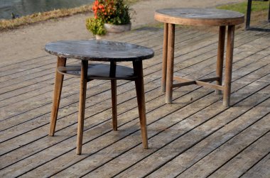 Su kenarında doğal ahşap sıralı ahşap banklar olan ahşap oturma alanı. Göletin yanındaki terasta piknik tezgahı ve kafe gibi yuvarlak masalar var. Liman iskelesi ördeklerle gölün yukarısına çıkıyor.