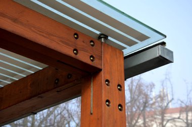Otobüs durağının ahşap yapısı, çardak pergola barınağı. Çatı ve duvarlar cam kaplı. Cam paslanmaz çelik eşleşmelerle sabitlenmiş. Tavan camı beyaz çizgili, güneş 