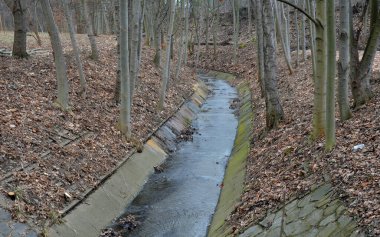Pahalı bir tahkimat çözümü ve bankanın beton panellerle kaplı bir kanala dönüştürülmesi. Su, orman arazisinden çok hızlı bir şekilde ivmelenir ve süzülür.