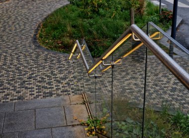 Kapı kolunun altından sarı ışıklı bir LED şerit çıkıyor. Merdiven korkuluğunun kenarı çerçevesiz cam panellerden yapılmış. Metal kulplarda paslanmaz çelik parmaklıklar