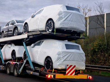 Yeni üretilmiş arabaları taşımak için bir karavan. Araba üreticileri plastik folyoya sarılı taşıma araçları. Bu daha pahalı arabaların boyalarını korur. O zaman pencerelerdeki fermuar...