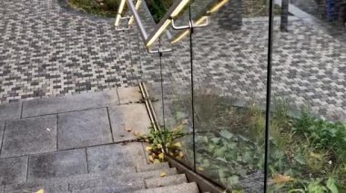 Kapı kolunun altından sarı ışıklı bir LED şerit çıkıyor. Merdiven korkuluğunun kenarı çerçevesiz cam panellerden yapılmış. Metal kulplarda paslanmaz çelik parmaklıklar