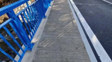  Dört beton vidayla yere sabitlenmiş dikey çit direkli köprü korkulukları. Parmaklıklar köprünün kenarından betona sabitlendi..