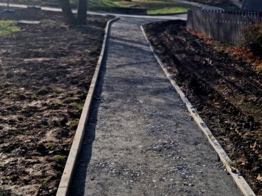 Kum tekeri. Bahçe el arabası bir işçi taşır ve park, orman ve toprak yolu onarmak için bej çakıl yığınlarının üzerine dökülür. Erozyon, yenilenmesi gereken çakılları alıp götürür.