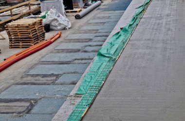 Çelik ızgaralardan yapılmış demir çubuklar karışımdan beton dökülüyor. Theodolite karışımın doğru katmanını ve düzlemini ölçer