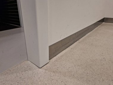 Hastaneler, mutfaklar ya da laboratuvarlar gibi ticari ya da endüstriyel ortamlarda sıkça rastlanan kombine ya da hijyenik süpürge kurulumu. Duvarın dibinde uzanan metal şerit.