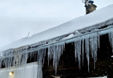 Buz sarkıtları çatıda eriyince oluşur, su kenarlara akar ve tekrar donar. Kışın soğuk iklimler. Şiddetli kar, evin çatısının kötü yalıtıldığını gösteriyor, donma koşulları....