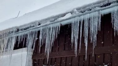 Buz sarkıtları çatıda eriyince oluşur, su kenarlara akar ve tekrar donar. Kışın soğuk iklimler. Şiddetli kar, evin çatısının kötü yalıtıldığını gösteriyor, donma koşulları....