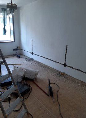 Tadilat yapılan bir oda, elektrik tesisatı için duvar değirmeni kanalları. Prizler ya da düğmeler için. Elmas patenli açı öğütücü, duvardaki oyukları kesiyor. oda