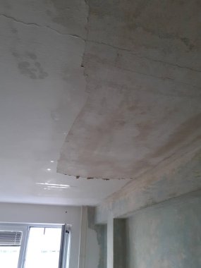 Tavanda yapısal sorunlar var. Renk değişimi, alçı soyma ve görünür çatlaklar bir süredir aktif olan bir sızıntıyı işaret ediyor..